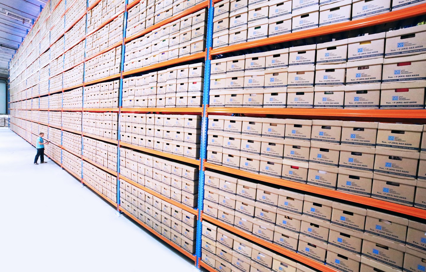 Man inspecting storage boxes in a vast warehouse.
